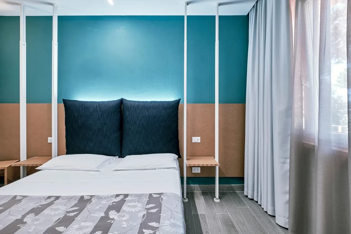 Camera small con arredi minimalisti, parete blu e letto matrimoniale.